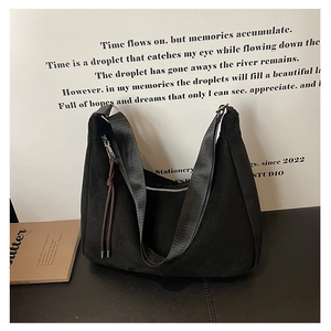 Detail of black suede tote bag with brown leather tassel and silver zipper closure