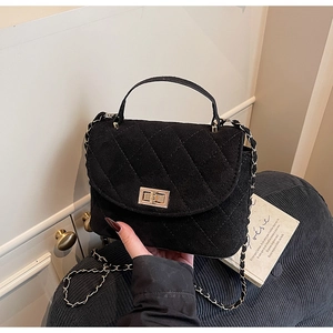 Détail du sac à main matelassé en daim noir avec fermoir doré et bandoulière chaîne