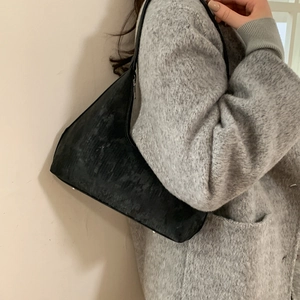 Chic black textured dumpling shoulder bag with slim strap on a gray wool coat