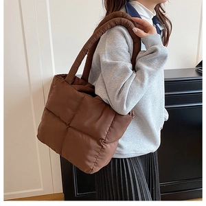 Close-up of dark coffee quilted puffer tote bag with soft padded texture and shoulder strap