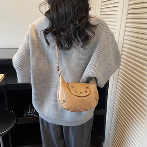 Sac bandoulière demi-lune en cuir PU marron avec rivets vintage porté par un mannequin