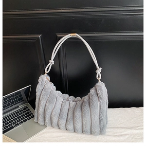 Détail du sac à bandoulière en fausse fourrure grise avec rayures et tissu blanc