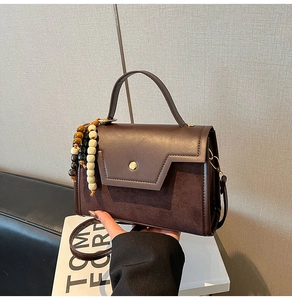Détail du sac bandoulière marron avec textures mixtes et breloque perlée décorative