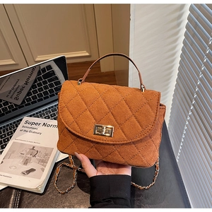 Détail d'un sac matelassé marron caramel avec fermoir doré et bandoulière en chaîne