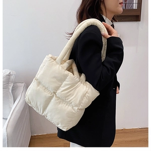 Side view of large cream quilted tote bag showing wide shoulder strap and soft texture