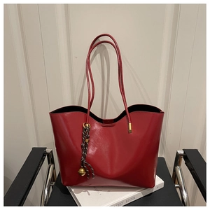 Detail of red tote bag featuring a unique wavy top edge and woven charm accessory