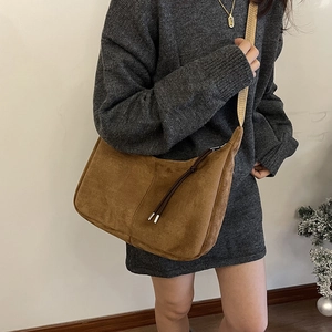 Brown faux suede half-moon shoulder bag with wide strap and tassel zipper detail