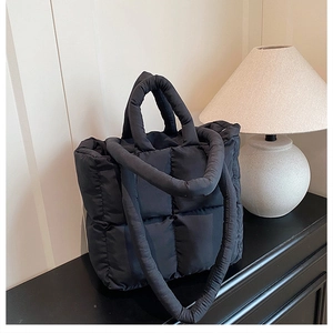 Close-up of black quilted puffer tote bag with soft padded texture and top handle