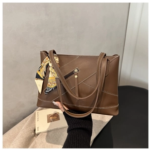 Detail of brown tote bag with contrast stitching and vintage scarf on the handle
