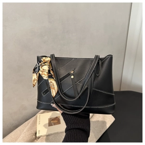 Detail of black tote bag with white stitching, outer pocket and decorative silk scarf