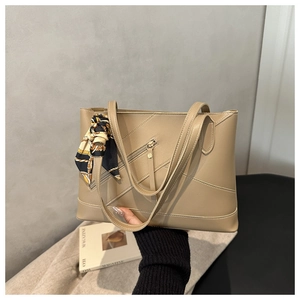 Detail of beige tote bag with geometric stitching and silk scarf on handle