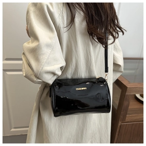 Détail du sac cylindre en cuir verni noir avec logo FASHION doré et bandoulière réglable