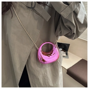 Chic pink metallic mini crossbody crescent bag with golden chain on grey trench coat