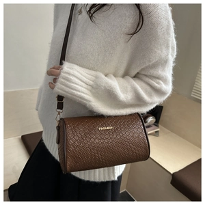 Detail of brown cylindrical crossbody bag with woven texture and gold fashion logo