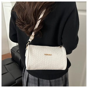 Détail d'un sac bandoulière blanc tissé avec logo doré et attaches de sangle dorées