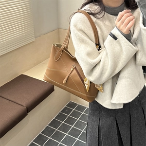 Brown leather tote bag with white stitching and floral scarf on a model indoors