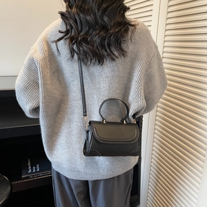 Minimalist black leather crossbody bag with top handle and gold hardware for women