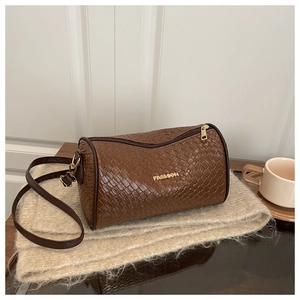 Détail de la texture tissée marron et du logo doré sur ce sac bandoulière tendance