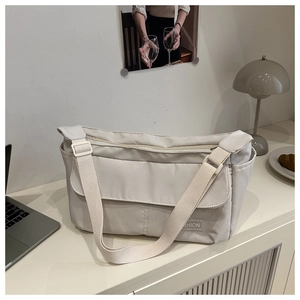 Detail view of the cream-white nylon tote bag with fashion label and adjustable strap