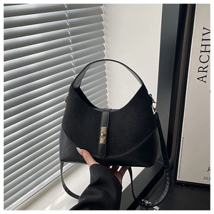 Dettaglio della borsa a conchiglia nera con texture in pelle mista e chiusura rotante dorata