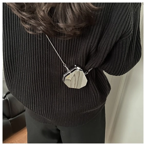Detail showing mirrored silver octagonal crossbody mini bag with chain on black sweater
