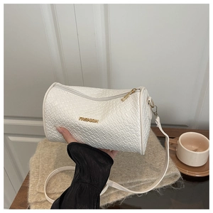 Détail du sac cylindre tressé blanc avec logo en métal doré et bandoulière en cuir