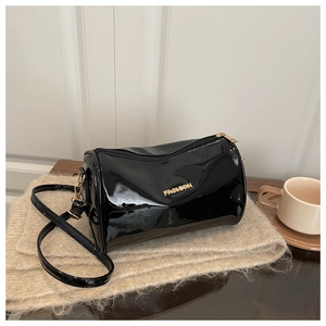 Détail du sac cylindrique en cuir verni noir avec logo Fashion doré sur tricot