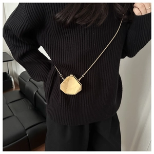 Close-up of golden octagonal mini chain bag on model wearing a black sweater
