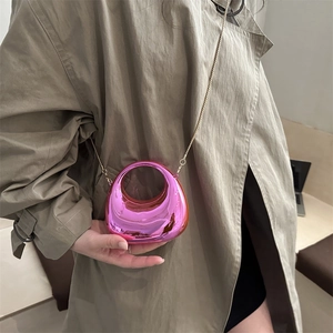 Mini magenta crescent acrylic lipstick bag with gold chain strap on khaki coat