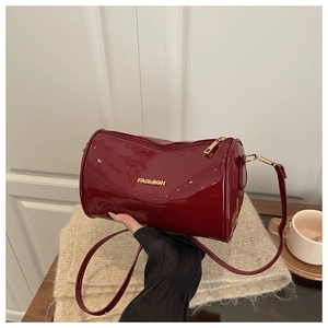 Détail du sac cylindrique en cuir verni rouge avec logo fashion doré et fini brillant