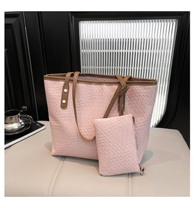 Detail of pink woven texture tote bag with brown leather handles and inner pouch