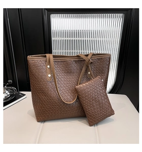 Close-up of brown woven tote bag set with matching clutch on a minimalist background