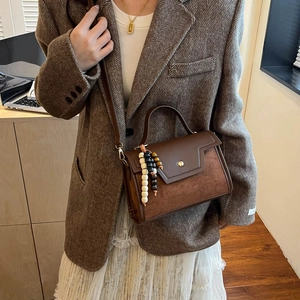 Sac bandoulière en cuir marron chic avec patchwork géométrique et pompon perlé