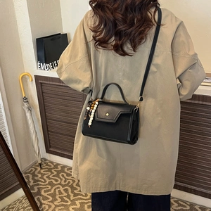 Sac à main chic en cuir noir avec boucle ronde et charm en perles sur la bandoulière