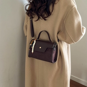 Sac à main vintage en cuir marron avec perles de bois colorées porté par mannequin