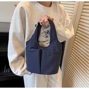 Detail of navy blue nylon tote bag featuring two large front pockets and portable handles