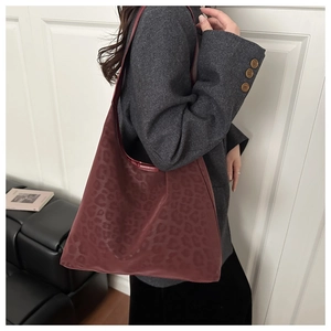 Detail of burgundy leopard print tote bag with satin finish shown on model shoulder