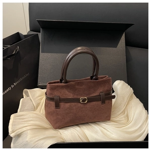 Détail du sac seau en daim marron avec poignée en cuir et boucle dorée élégante