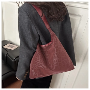 Detail of burgundy leopard print hobo bag with wide shoulder strap in a stylish setting