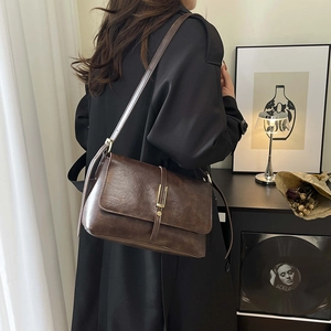 Borsa a tracolla retrò in pelle marrone scuro con chiusura dorata indossata da modella