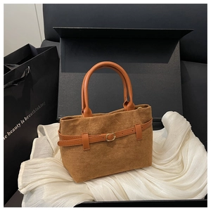 Détail d'un sac seau en daim marron avec poignées en cuir et boucle dorée élégante