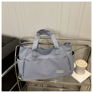 Dettaglio della borsa tote blu multitasche in nylon resistente con etichetta alla moda