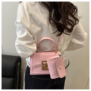 Detailed view of pink crossbody bag set with gold geometric buckles on a clean background