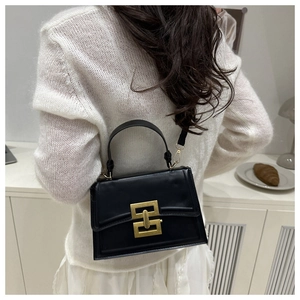 Detail of a chic black leather crossbody bag featuring a striking gold geometric metal clasp