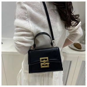 Detailed view of black leather crossbody bag with distinctive gold geometric lock buckle