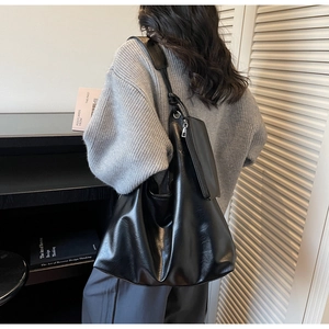 Detail of a large black soft leather hobo bag with a matching small zipper pouch