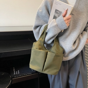 Olive green nylon tote bag with multi-pocket design shown in a casual lifestyle setting