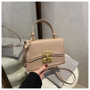 Detail of minimalist beige crossbody bag with gold geometric buckle and leather handle