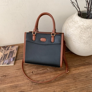 Grand sac à main bicolore noir et marron sur une table avec des objets de déco