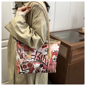 Detailed view of women's tote bag featuring vibrant street style graffiti and slim brown straps